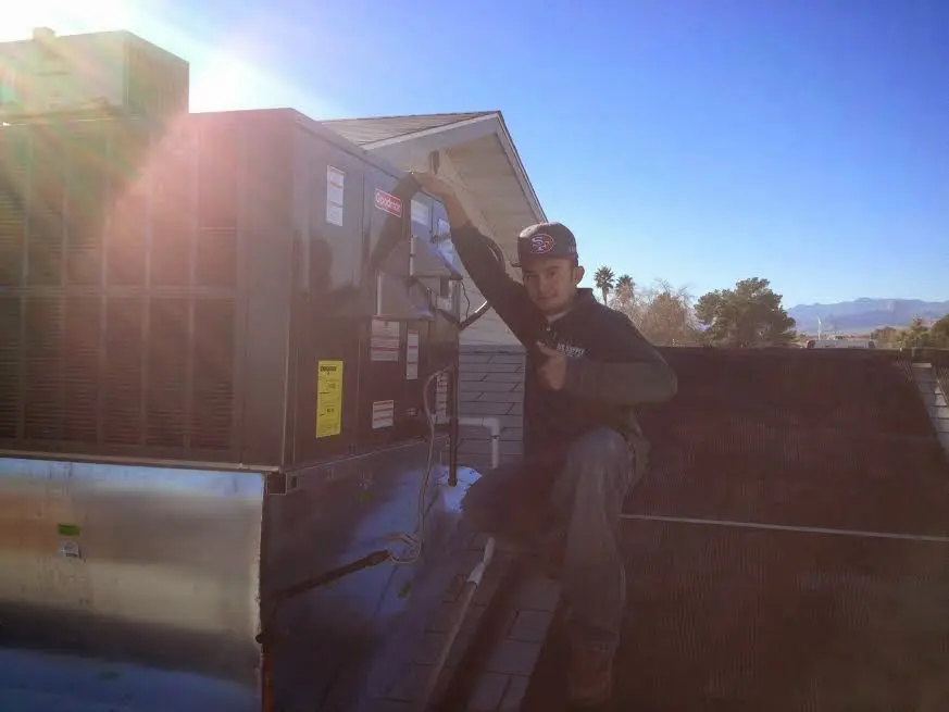 HVAC technician performing AC Tune-Up on a rooftop unit in Rose